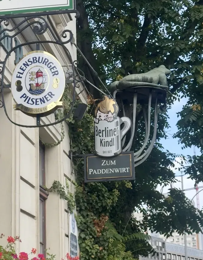 Krötenfigur und historische Ausleger an der Fassade des Restaurants Zum Paddenwirt im Nikolaiviertel